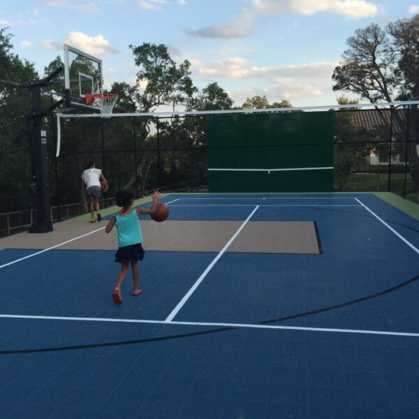 A multi use sport court with a tennis net, pickleball, and basketball court builder in Houston